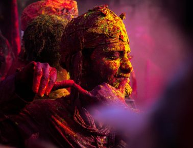 Colorful Holi celebration in Vrindavan with people covered in vibrant powder.