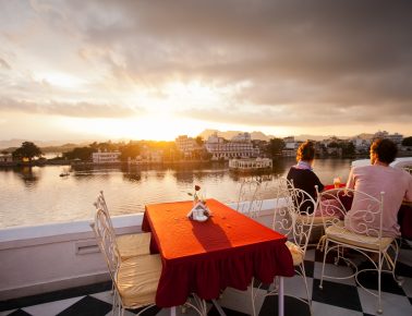 a couple enjoying sunset from the jagat nivas terrace across the pichola lake